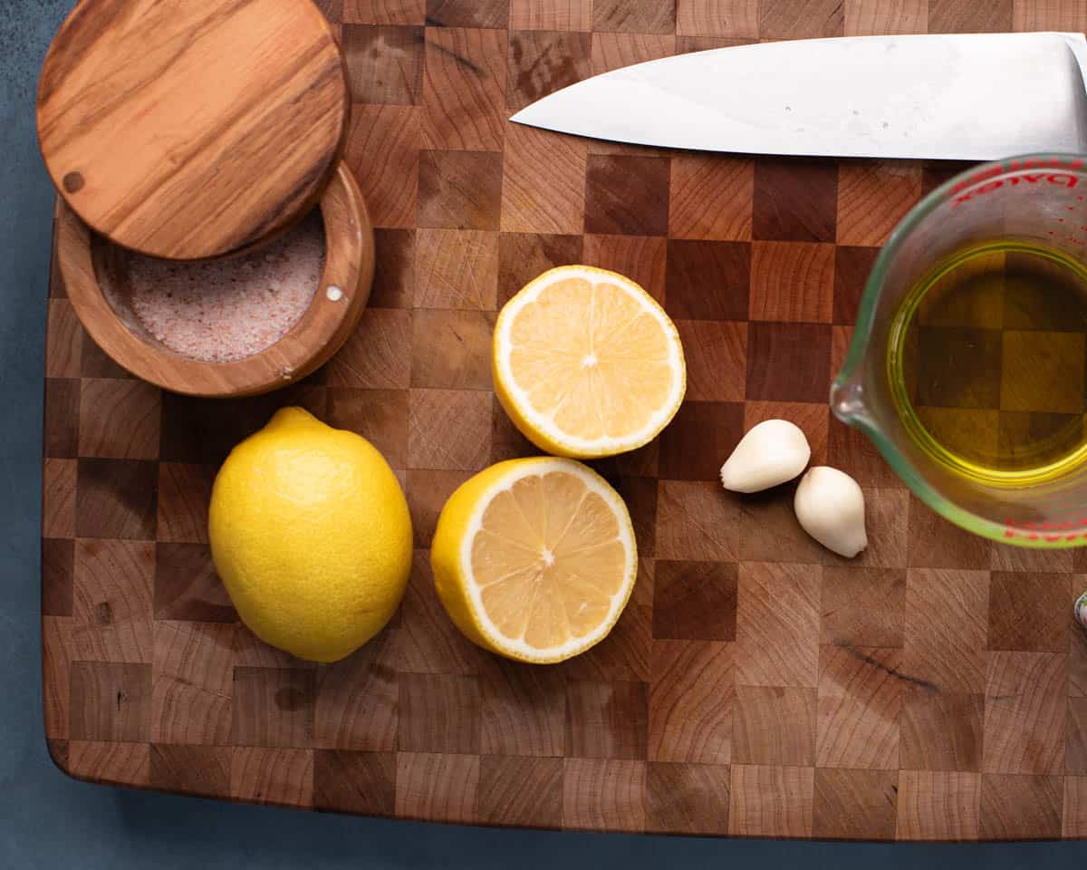 lemons on cutting board with garlic, avocado oil, and salt