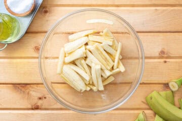 unripe banana cut into strips tossed with olive oil and salt in bowl