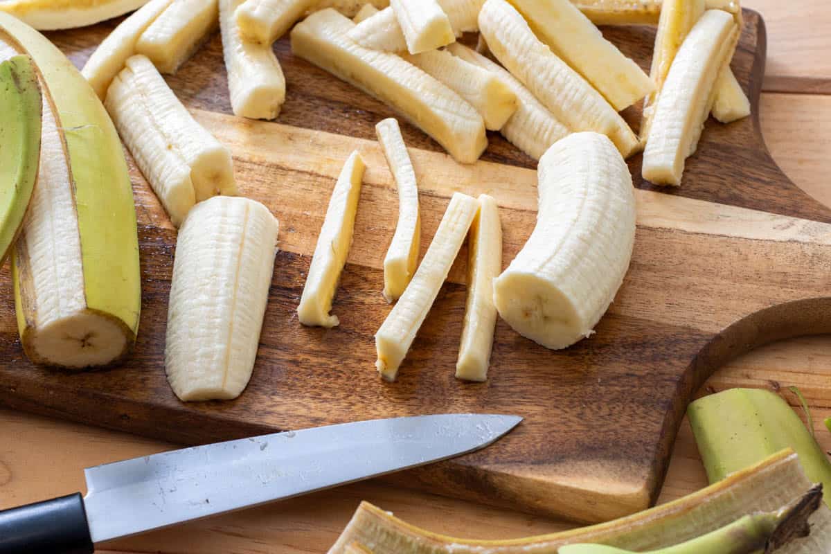 peeling green bananas and slicing into French fries