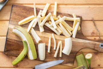 peeling green banana and slicing into fries
