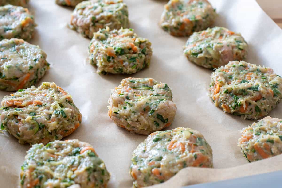 chicken mixture shaped into nuggets on parchment lined baking sheet