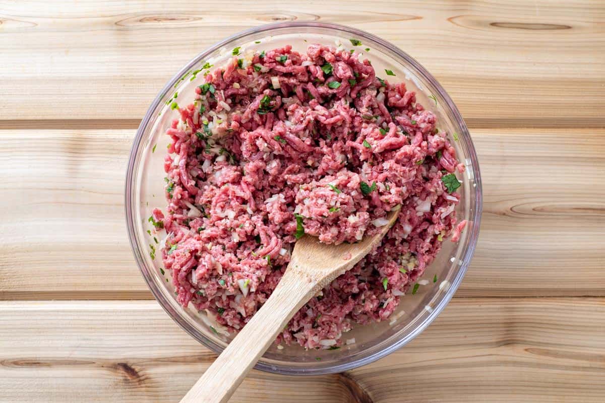 ground beef with chopped onion, garlic, ginger in bowl