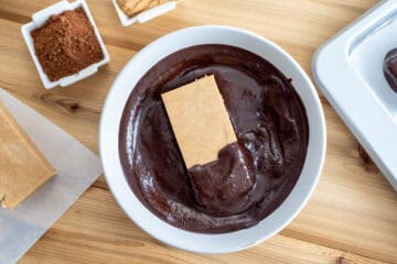 protein bar dipped in bowl of liquid carob mixture