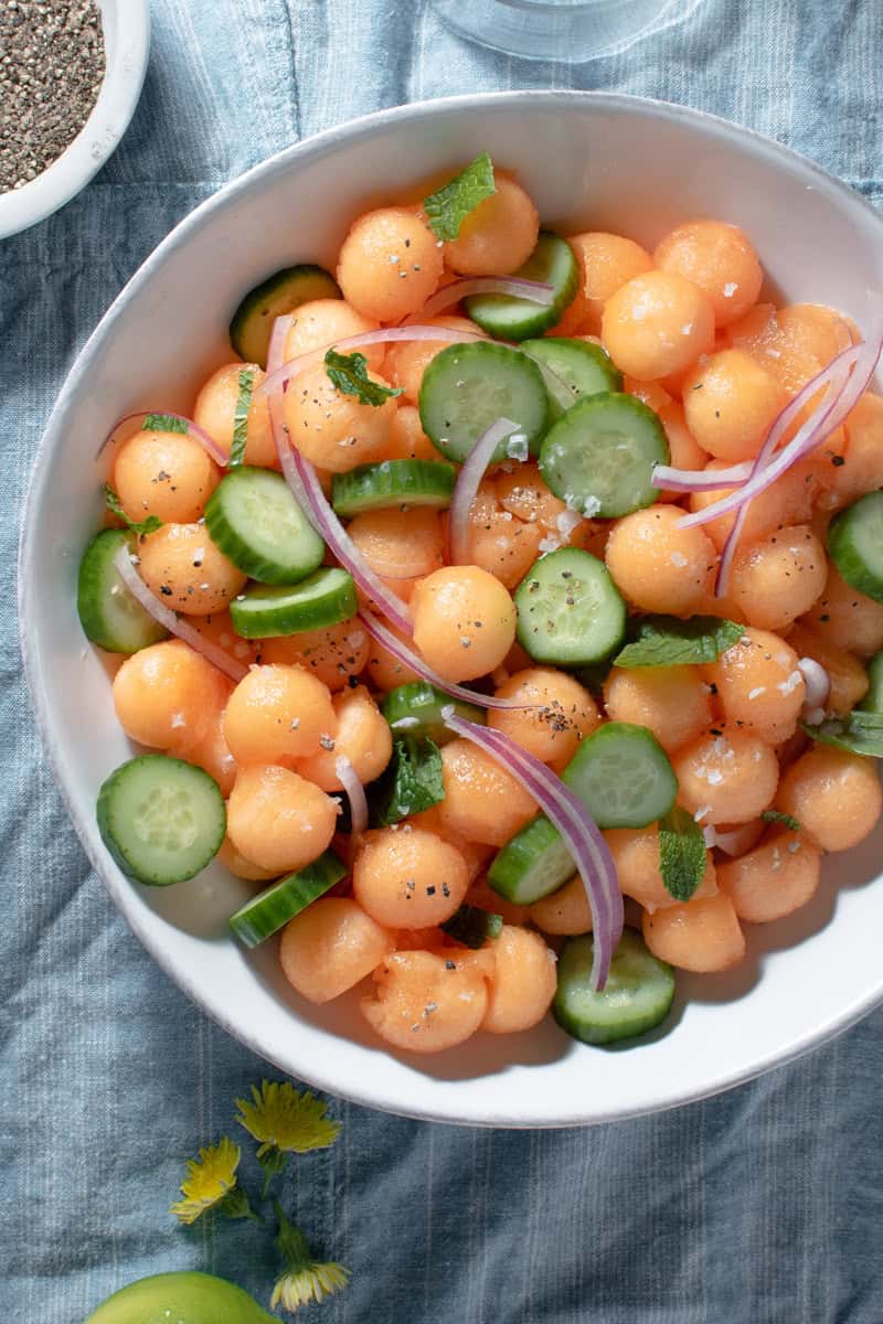 cantaloupe cucumber mint and red onion in a salad bowl