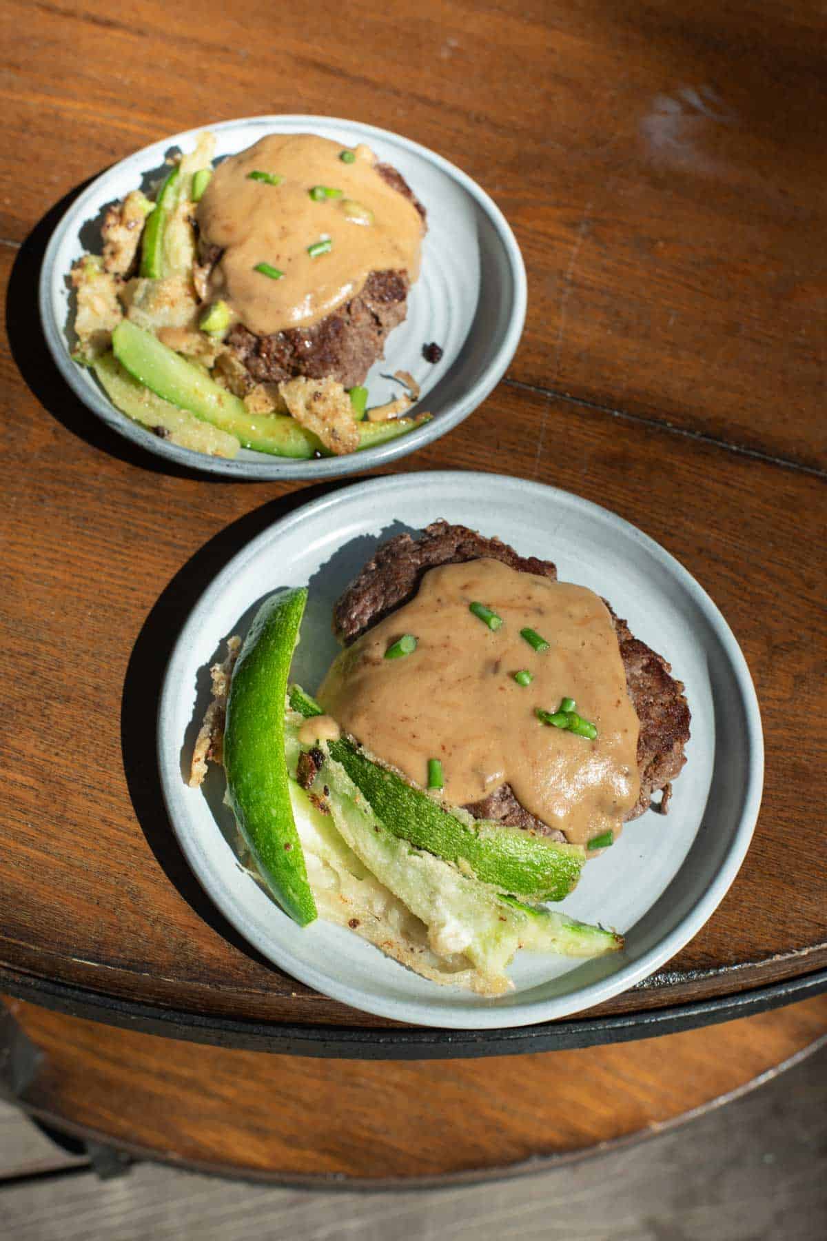 burgers with nutritional yeast sauce on top and zucchini tempura fries