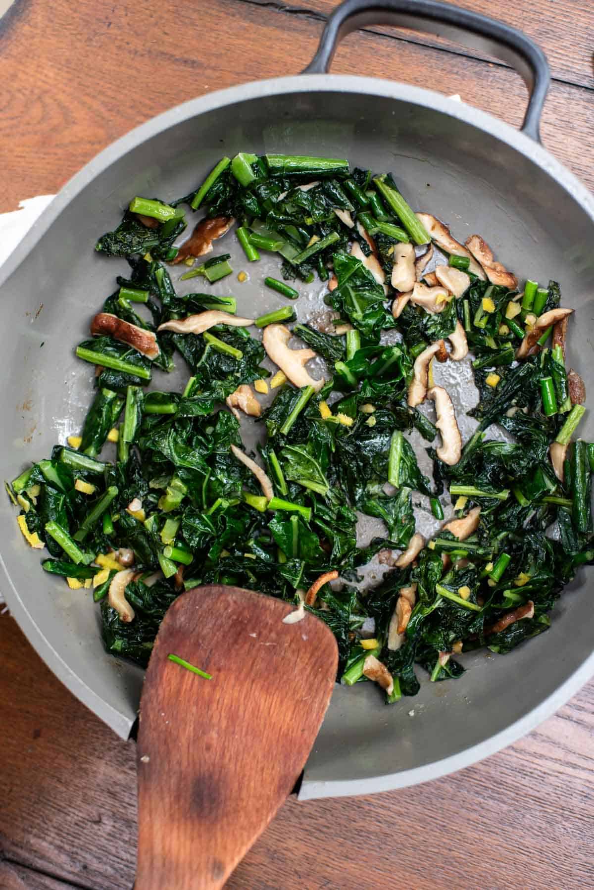 sauteed kale with shiitake mushrooms, ginger, and green garlic in skillet